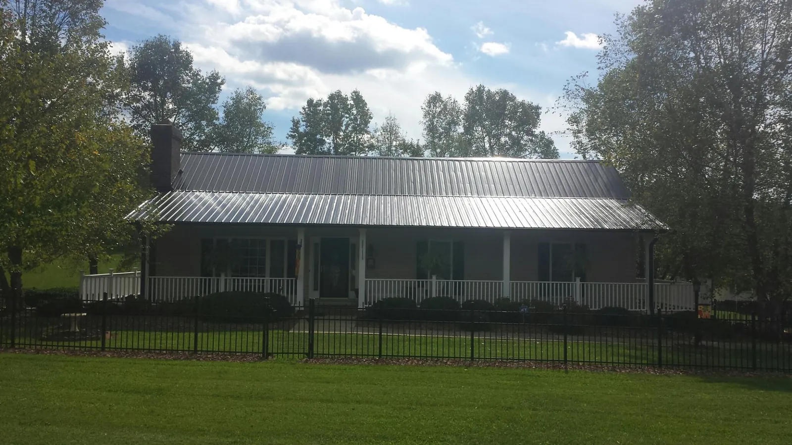Gray metal roof on a brick ranch with a full width front porch — Gutter Guard Installation work by our crew in Granger