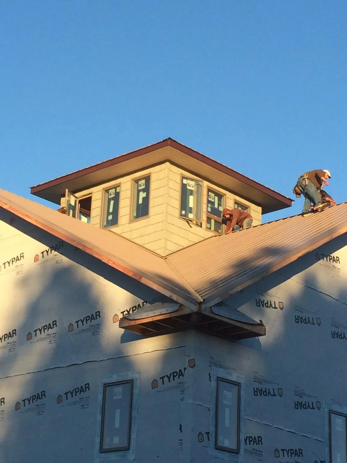 Roofers working around a rooftop cupola on a new metal roof at sunset — Roof Waterproofing in Granger by Roofing Brothers